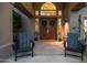 Front entry with double wood doors, flanked by black chairs and plants at 15250 S 20Th Pl, Phoenix, AZ 85048