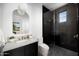 Modern bathroom with black tiled shower, concrete countertop, and stylish mirror at 4445 E Roma Ave, Phoenix, AZ 85018