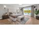 Primary bedroom featuring a king-size bed, bench, backyard views, and an accent rug on wood floors at 9136 N 81St St, Scottsdale, AZ 85258