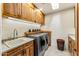 Well-lit laundry room offers gray front load washer/dryer, wood cabinetry, and large sink at 1084 N Boulder Dr, Carefree, AZ 85377