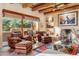 Charming living room with fireplace, beamed ceiling, and large windows providing natural light at 1084 N Boulder Dr, Carefree, AZ 85377