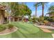 Expansive backyard featuring a putting green, lush landscaping, a pool, and patio seating areas at 11505 E Cochise Dr, Scottsdale, AZ 85259