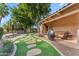 Backyard view highlights a lush green artificial lawn with stone stepping pavers leading to patio with seating at 11505 E Cochise Dr, Scottsdale, AZ 85259