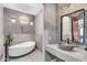 Stylish bathroom featuring a soaking tub, vessel sink, designer lighting, and decorative stone wall at 11505 E Cochise Dr, Scottsdale, AZ 85259