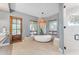 Beautiful bathroom featuring a soaking tub with a large window view and decorative hanging light fixture at 11505 E Cochise Dr, Scottsdale, AZ 85259