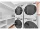 Well-organized laundry room features stacked Whirlpool washer and dryer units and ample storage shelves at 11505 E Cochise Dr, Scottsdale, AZ 85259