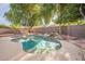 Private backyard pool with a rock feature, surrounded by lush trees, offering a tranquil outdoor oasis at 1225 E San Angelo Ave, Gilbert, AZ 85234