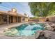 Backyard showcases a unique pool with rock accents, framed by a cozy patio and lush landscaping at 1225 E San Angelo Ave, Gilbert, AZ 85234