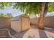 Backyard shed with a shingled roof, surrounded by crushed granite, offering practical storage with nice landscaping at 1225 E San Angelo Ave, Gilbert, AZ 85234