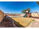 Fenced backyard featuring a built in playground, pool, and beautiful landscaping at 1370 S 228Th Ln, Buckeye, AZ 85326