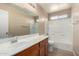 Bright bathroom features a wood vanity, a large mirror, and a shower-tub combo at 1370 S 228Th Ln, Buckeye, AZ 85326