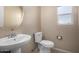 Cozy half bathroom featuring a pedestal sink, toilet, and a small window for natural light at 1370 S 228Th Ln, Buckeye, AZ 85326
