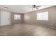 Bright living room featuring three windows, modern ceiling fan, and sleek laminate flooring at 1370 S 228Th Ln, Buckeye, AZ 85326