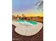 Backyard pool featuring a unique shape, desert landscaping, and brick perimeter wall at 1370 S 228Th Ln, Buckeye, AZ 85326
