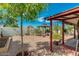 Backyard features a covered patio, gravel landscaping, and mature trees at 13830 W Fargo Dr, Surprise, AZ 85374