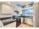 Updated kitchen features sleek black appliances, granite counters, tile backsplash, and white cabinetry at 1905 E University Dr # 216, Tempe, AZ 85288
