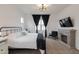 Comfortable bedroom with a fireplace, TV, black metal bed frame, soft carpet, and bright natural light at 34395 N Cherrystone Dr, San Tan Valley, AZ 85144