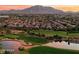 Expansive aerial view of the community with lush golf course, water features, and mountain views at sunset at 3882 E Andalusia Ave, Gilbert, AZ 85298