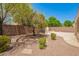 Landscaped backyard featuring mature tree, brick wall, and outdoor fireplace at 4286 E Buckboard Rd, Gilbert, AZ 85297