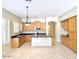 Well-lit kitchen with stainless steel appliances, wood cabinetry, tile flooring, and a practical kitchen island at 4286 E Buckboard Rd, Gilbert, AZ 85297