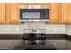 Close-up highlighting the stainless steel microwave and range set amongst the oak cabinetry and dark countertop at 4286 E Buckboard Rd, Gilbert, AZ 85297