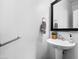 Clean, half bathroom featuring a pedestal sink, mirror, and accessible handrail at 11434 W St John Rd, Surprise, AZ 85378