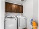 Well-lit laundry room equipped with front-load washer, dryer and overhead cabinets at 11434 W St John Rd, Surprise, AZ 85378