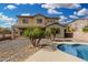 Beautiful backyard with a sparkling pool, mature palm trees, and a covered patio area at 15357 W Post Cir, Surprise, AZ 85374
