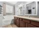 Bathroom featuring dual sinks, updated cabinetry, framed mirrors and a bathtub at 15357 W Post Cir, Surprise, AZ 85374
