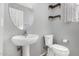 The powder room showcases a pedestal sink, toilet, floating shelves and modern fixtures at 15357 W Post Cir, Surprise, AZ 85374