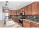 Close-up of the kitchen featuring stainless steel appliances, stone backsplash, and wooden cabinets at 15357 W Post Cir, Surprise, AZ 85374
