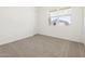 Bright, carpeted bedroom featuring a large window offering lots of natural light and a view of the neighborhood at 17624 W Pierson St, Goodyear, AZ 85395