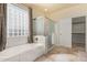 Bright bathroom featuring a soaking tub, glass block window, and separate shower at 1870 E Indigo Dr, Chandler, AZ 85286