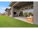 Home's backyard featuring artificial turf, outdoor seating, and sliding glass doors at 19726 E Vallejo St, Queen Creek, AZ 85142