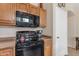 Kitchen featuring an electric range, black microwave, and wood cabinetry at 2635 W Angel Way, San Tan Valley, AZ 85144