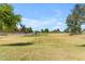 Expansive grassy park featuring mature trees, a covered picnic area, and a playground under a clear blue sky at 2635 W Angel Way, San Tan Valley, AZ 85144