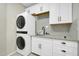 A laundry room featuring a stackable washer and dryer unit, ample cabinets, and sink at 41309 N Belfair Way, Anthem, AZ 85086