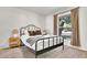 Bedroom with black iron bed frame, plush carpet, and natural light from a large window at 7028 N 12Th Way, Phoenix, AZ 85020