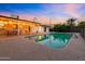 Backyard with covered patio, a large, sparkling pool, and serene evening ambiance at 7028 N 12Th Way, Phoenix, AZ 85020