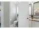 Bright bathroom features a white toilet, marble floors and sink with gray cabinets at 7807 W Palm Ln, Phoenix, AZ 85035