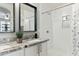 Bathroom featuring a white shower, vanity with granite countertops, framed mirror, and a plant at 7807 W Palm Ln, Phoenix, AZ 85035