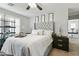 Main bedroom with neutral walls, ceiling fan, tufted headboard, shuttered windows, and nightstands at 7807 W Palm Ln, Phoenix, AZ 85035
