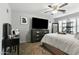 Main bedroom with ceiling fan, shuttered windows, TV and dark wood dresser with white bedding at 7807 W Palm Ln, Phoenix, AZ 85035