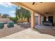 Covered back patio has ceiling fan and view to backyard with mature trees at 9429 E Nacoma Dr, Sun Lakes, AZ 85248