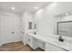 Bright bathroom featuring dual sinks, white cabinets, wood look floors, and modern fixtures at 9522 W Luxton Ln, Tolleson, AZ 85353
