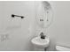 Elegant powder room featuring a pedestal sink, round mirror, and modern fixtures at 9522 W Luxton Ln, Tolleson, AZ 85353