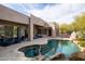 Desert home backyard with covered patio, a barbecue, and a large pool with rock features at 9626 E Peak View Rd, Scottsdale, AZ 85262