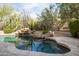 Backyard pool featuring natural stone waterfall, lush desert landscaping, and integrated hot tub at 9626 E Peak View Rd, Scottsdale, AZ 85262