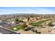 Expansive aerial showcasing a lush golf course, mature trees, and city skyline at 12814 W Shadow Hills Dr, Sun City West, AZ 85375