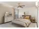 This bedroom features a ceiling fan, a dresser with a mirror, and a bed with an earth tone color palette at 12814 W Shadow Hills Dr, Sun City West, AZ 85375
